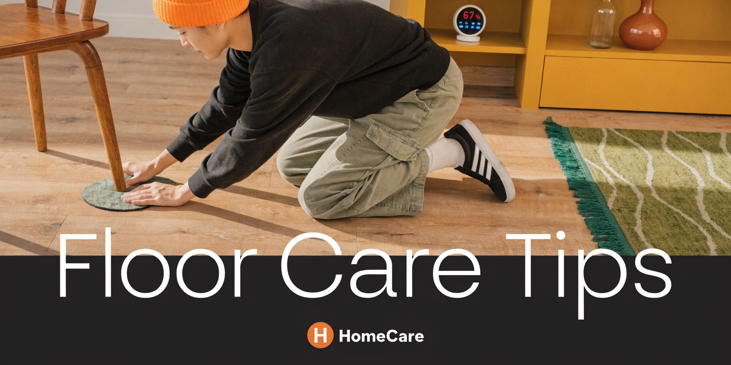 A person kneeling on a hardwood floor placing a protective felt pad under a chair leg.
