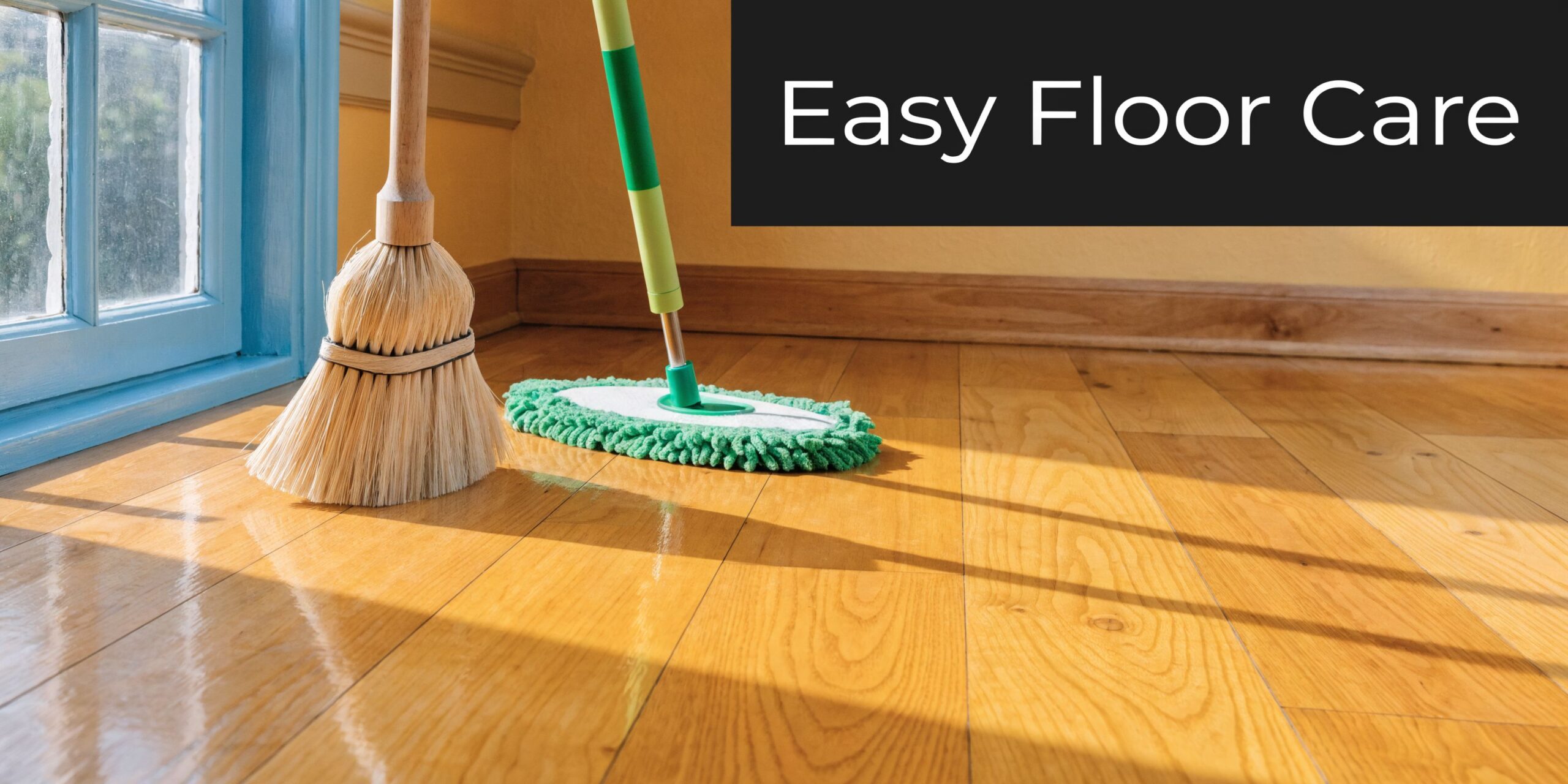 A wooden broom and a green microfiber mop resting on polished light brown hardwood flooring.