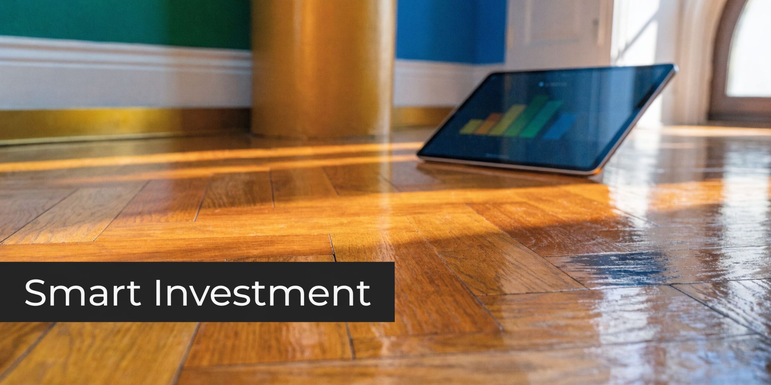 A digital tablet displaying a colorful bar chart rests on a polished, warm-toned wooden herringbone floor.
