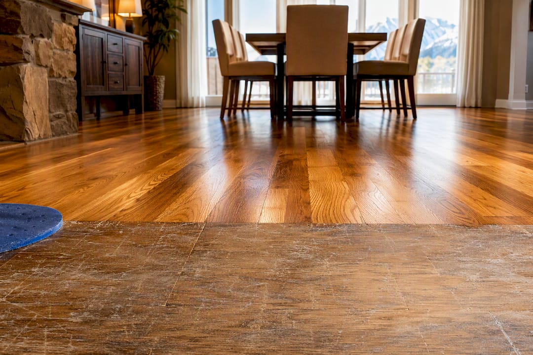 Refinished hardwood beside worn scratched flooring