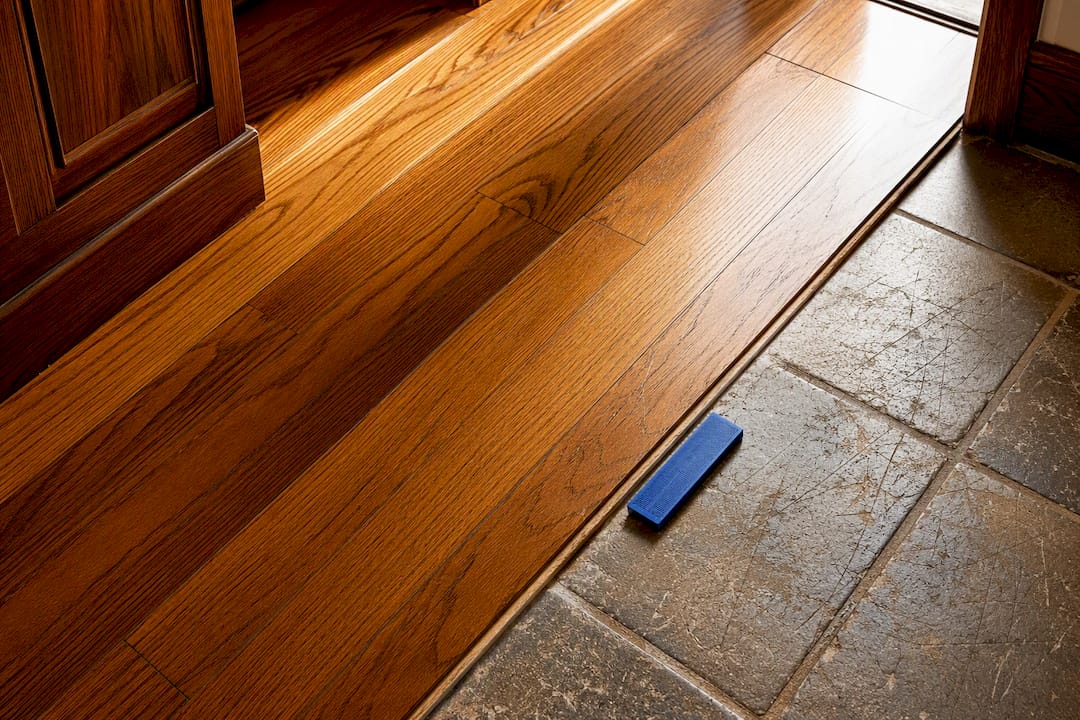 Refinished hardwood beside worn floor transition