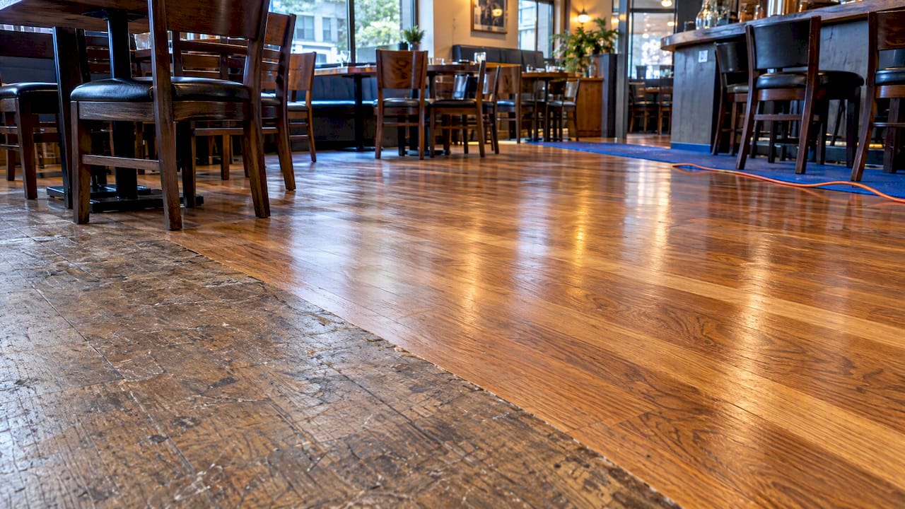 Worn restaurant floor beside restored hardwood boards